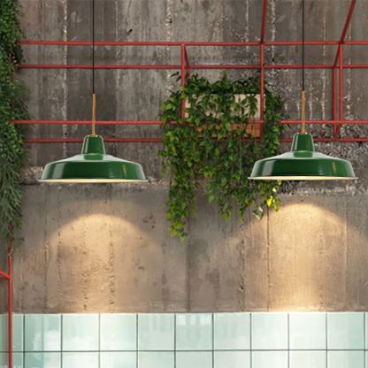 Two Cairns green metal pendant lights against a textured wall.