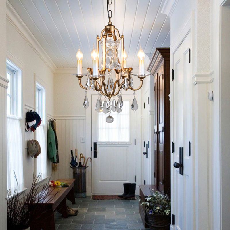 Crystal chandelier in entryway with bench and accessories.
