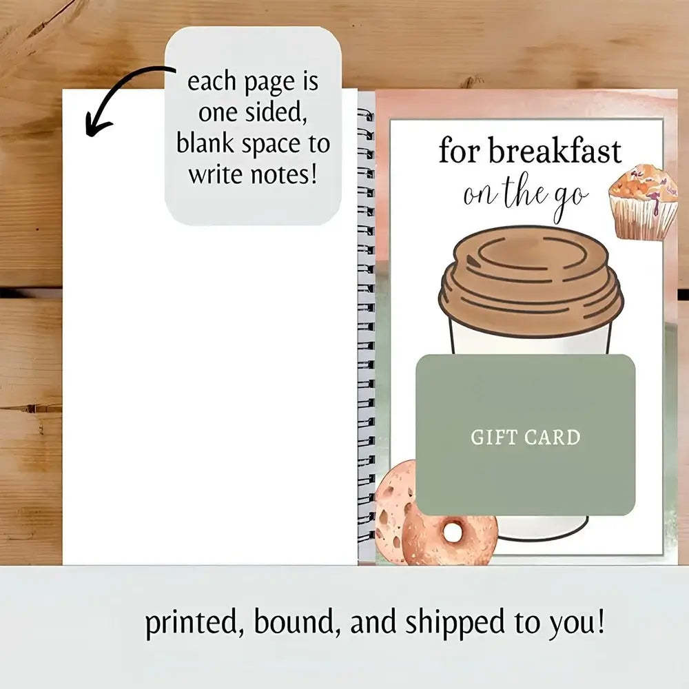 A spiral-bound notebook shown open on a wooden surface, with the left page blank and a right page featuring a coffee cup illustration, the text 'for breakfast on the go,' a green 'GIFT CARD' block, and donut graphics. A note says each page is one sided, blank space to write notes!, and printed, bound, and shipped to you!.