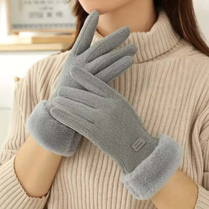 A person wearing a pair of gray fleece winter gloves with soft fuzzy cuffs, holding one glove in front of the other.