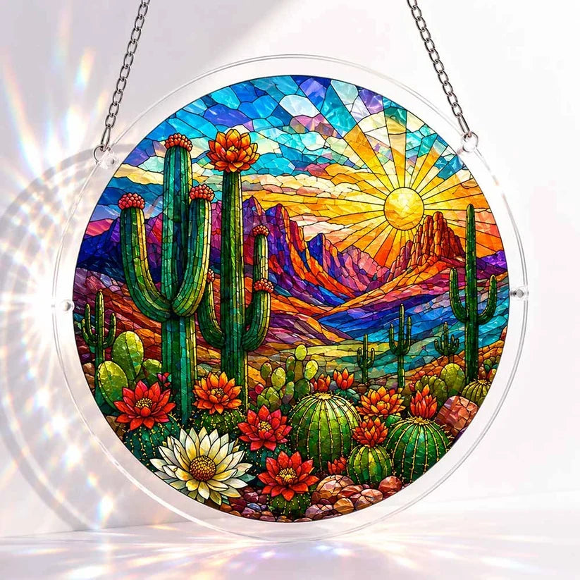 A round acrylic suncatcher depicting a desert sunset with saguaro cacti blooming cactus flowers and rocky mountains