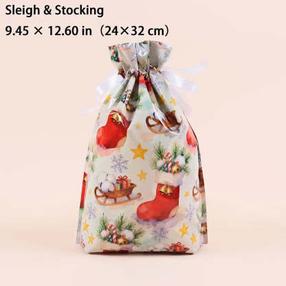 A Christmas-themed drawstring gift bag with a festive print of red stockings, sledding, candy canes, pine branches, and snowflakes on a light background. The bag is tied with a white ribbon and has text at the top reading 'Sleigh & Stocking