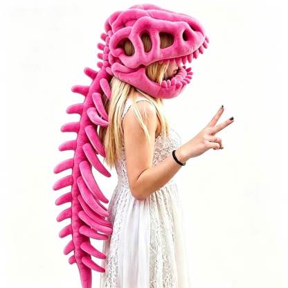 A woman in a white lace dress wearing a large pink dinosaur skull and spine plush costume hat, posing against a plain white background.