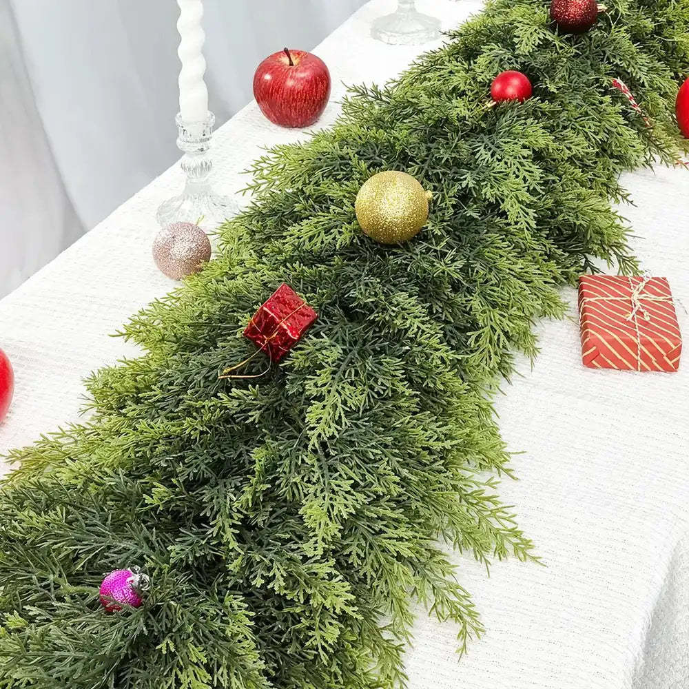 Decorative green garland with red and gold ornaments on a white surface