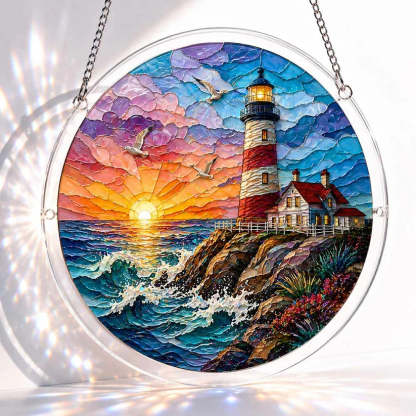 A round acrylic suncatcher showing a red and white lighthouse on rocky cliffs at sunset with waves and seagulls