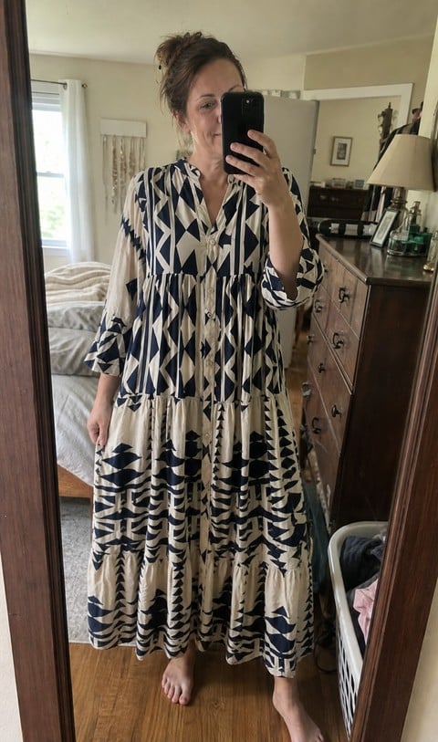 Woman checking the blue geometric maxi dress in a bedroom mirror