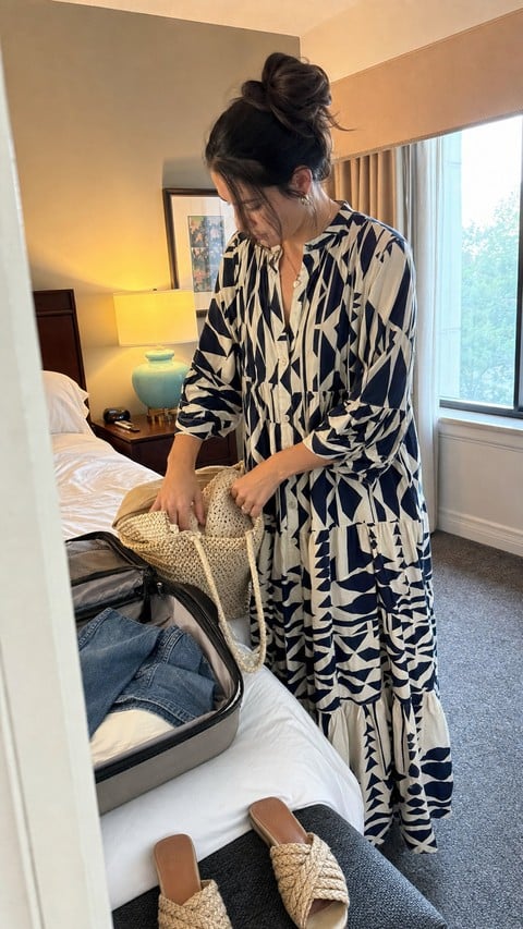 Woman packing a woven tote while wearing the blue geometric maxi dress