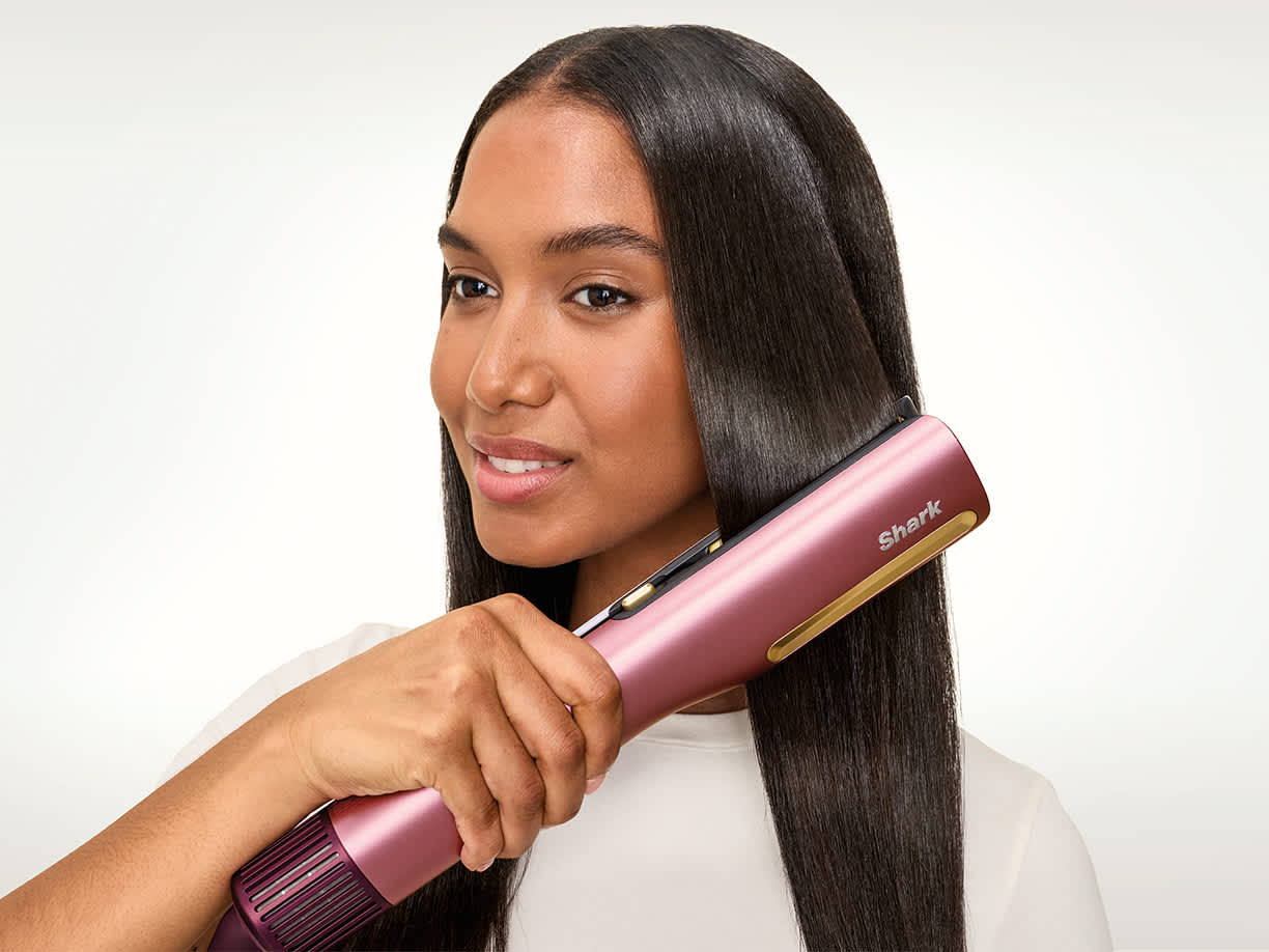 Femme qui tient un Shark SilkiPro Straight et qui lisse ses cheveux