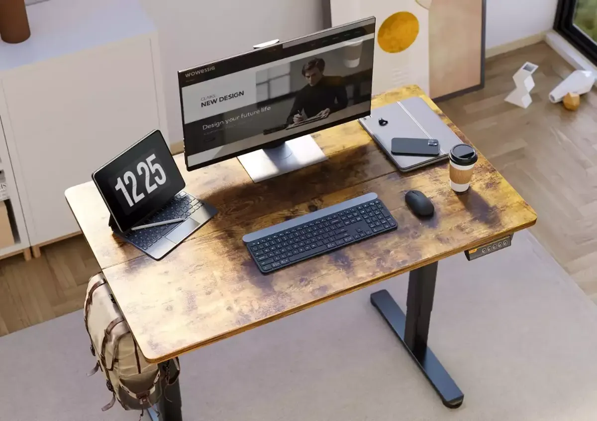 Modern workspace featuring a wooden desk with a computer monitor, laptop, keyboard, mouse, and a coffee cup.