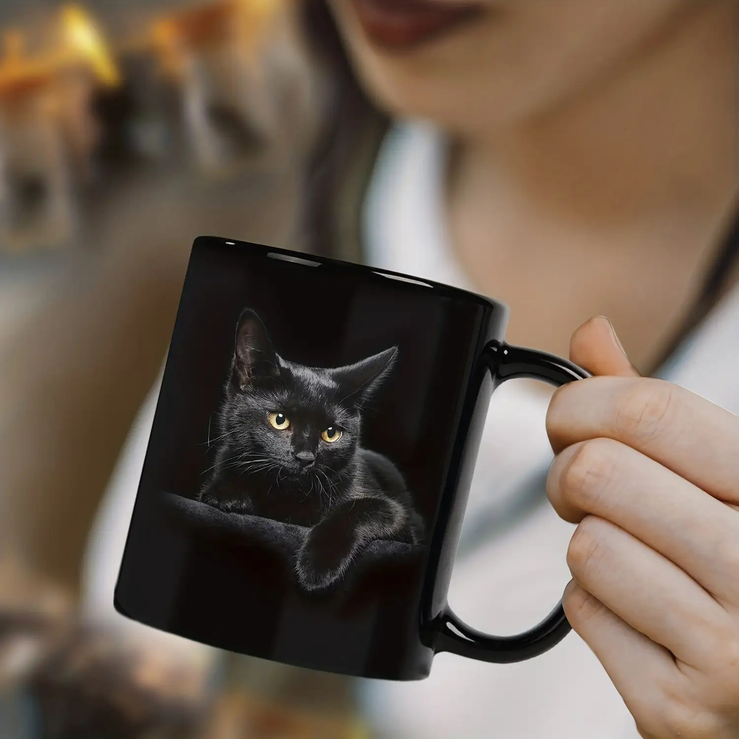 Black cat mug held by hand for coffee or tea