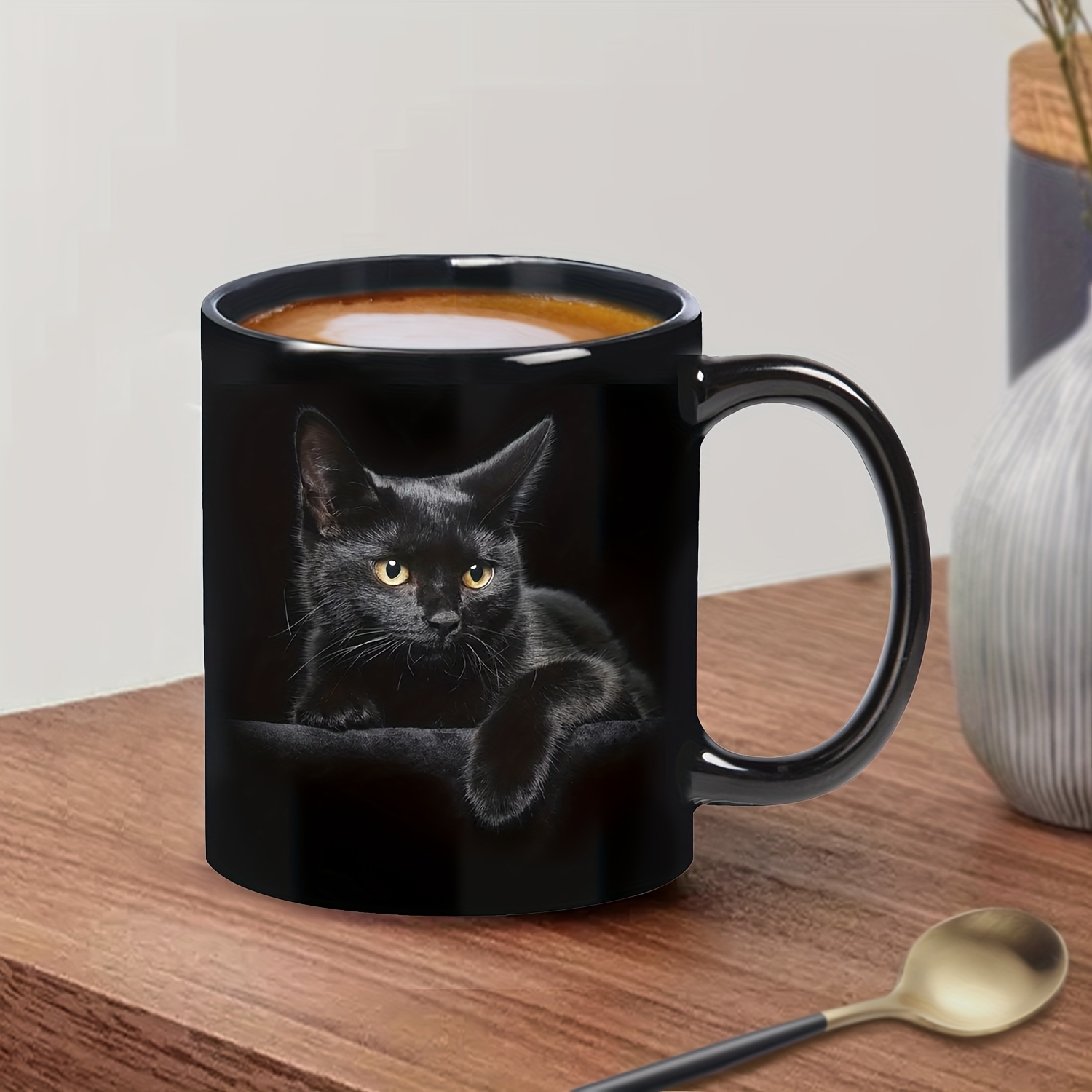 Black cat coffee mug on table with drink and spoon