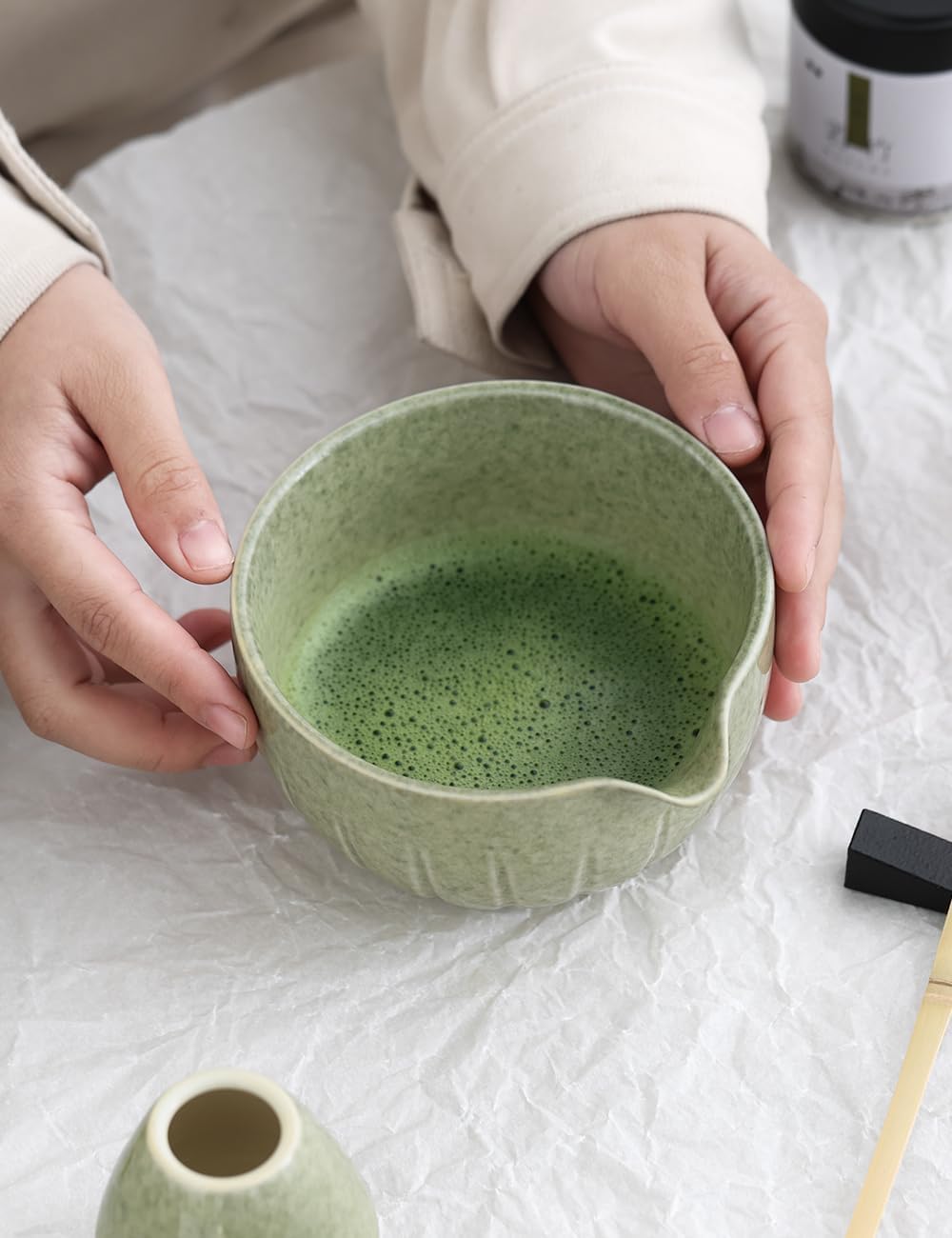 Foamed matcha served in the 15 oz ceramic bowl beside the bamboo whisk