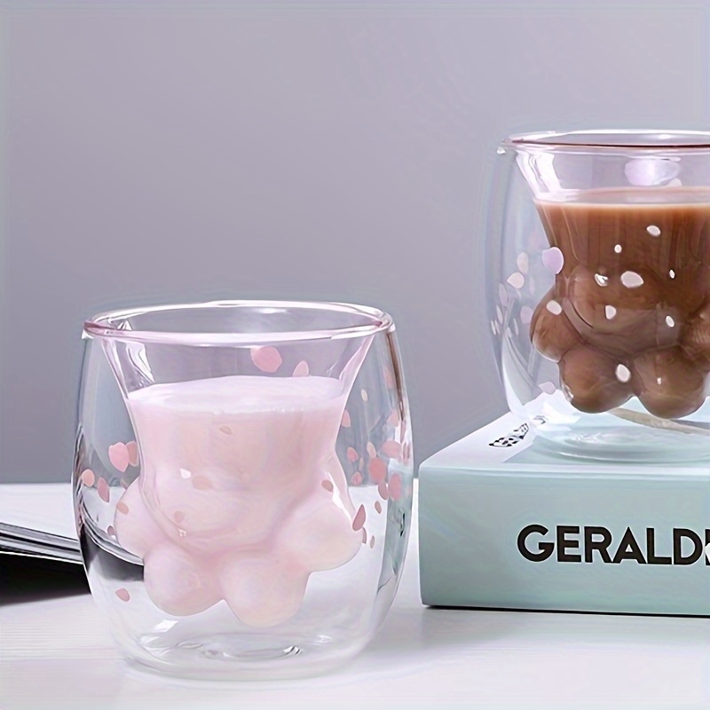 Cat paw glass cup with milk and coffee on tabletop