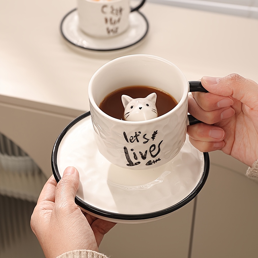 Cat mug with cat inside held with matching saucer