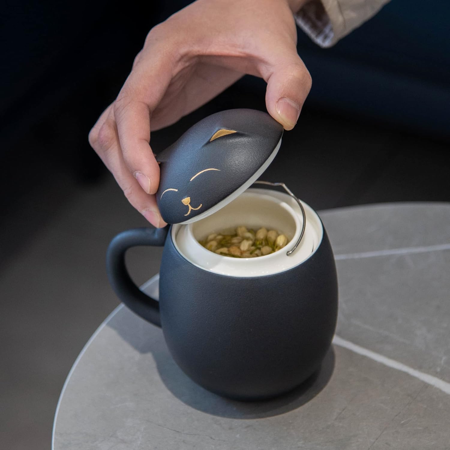 Ceramic tea cup with cat-shaped styling arranged for desk brewing
