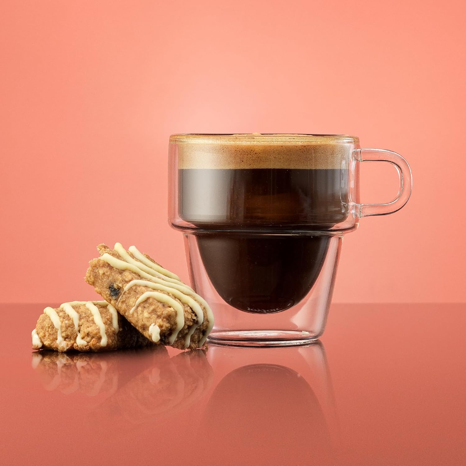 5 oz stackable espresso cup on a coral background with biscotti beside it