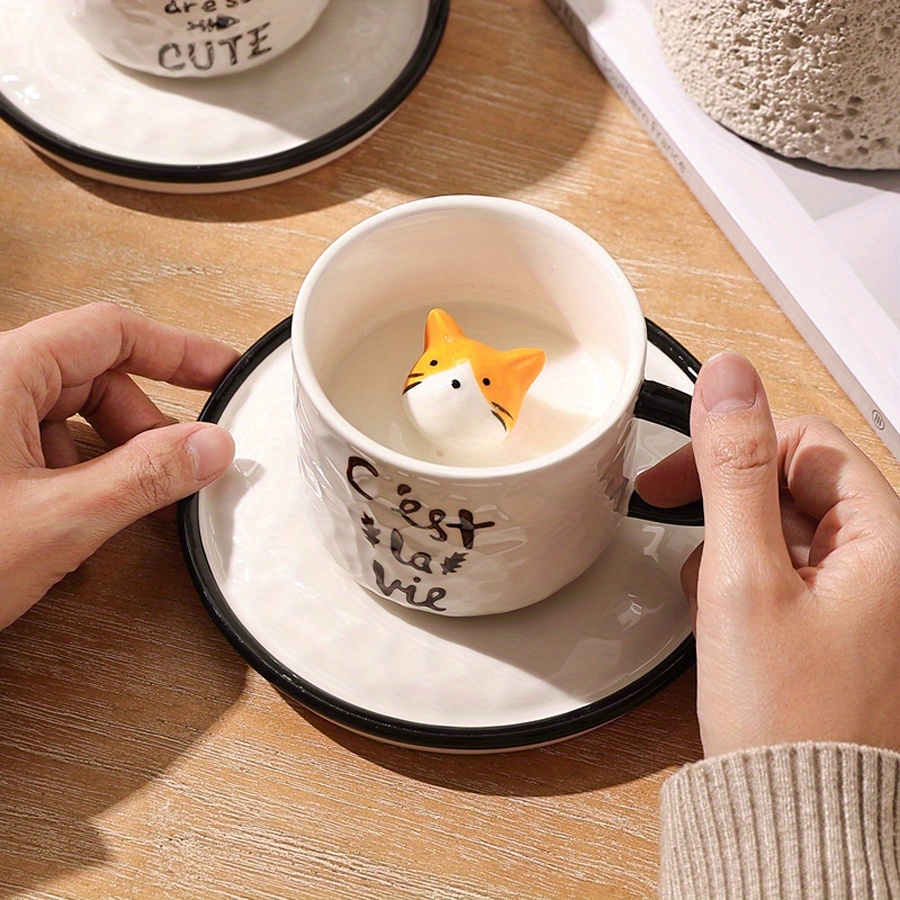 Cat mug with hidden 3D kitten inside held by hand