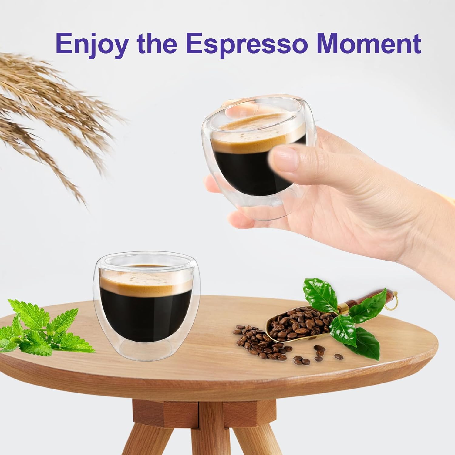 One 3 oz clear double wall espresso cup shown in hand with a second cup on the table