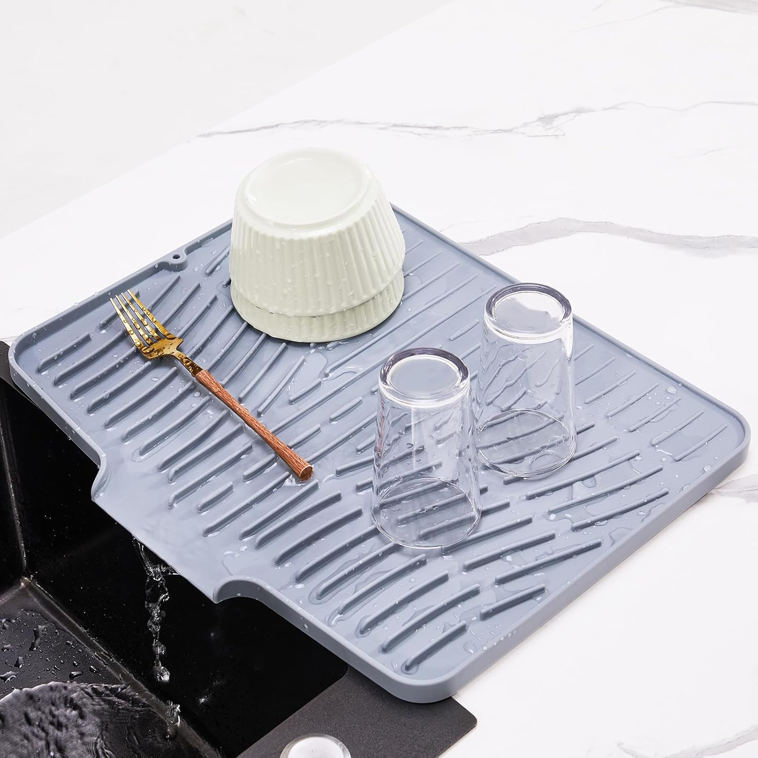silicone drying mat with dishes and cups placed on top draining water