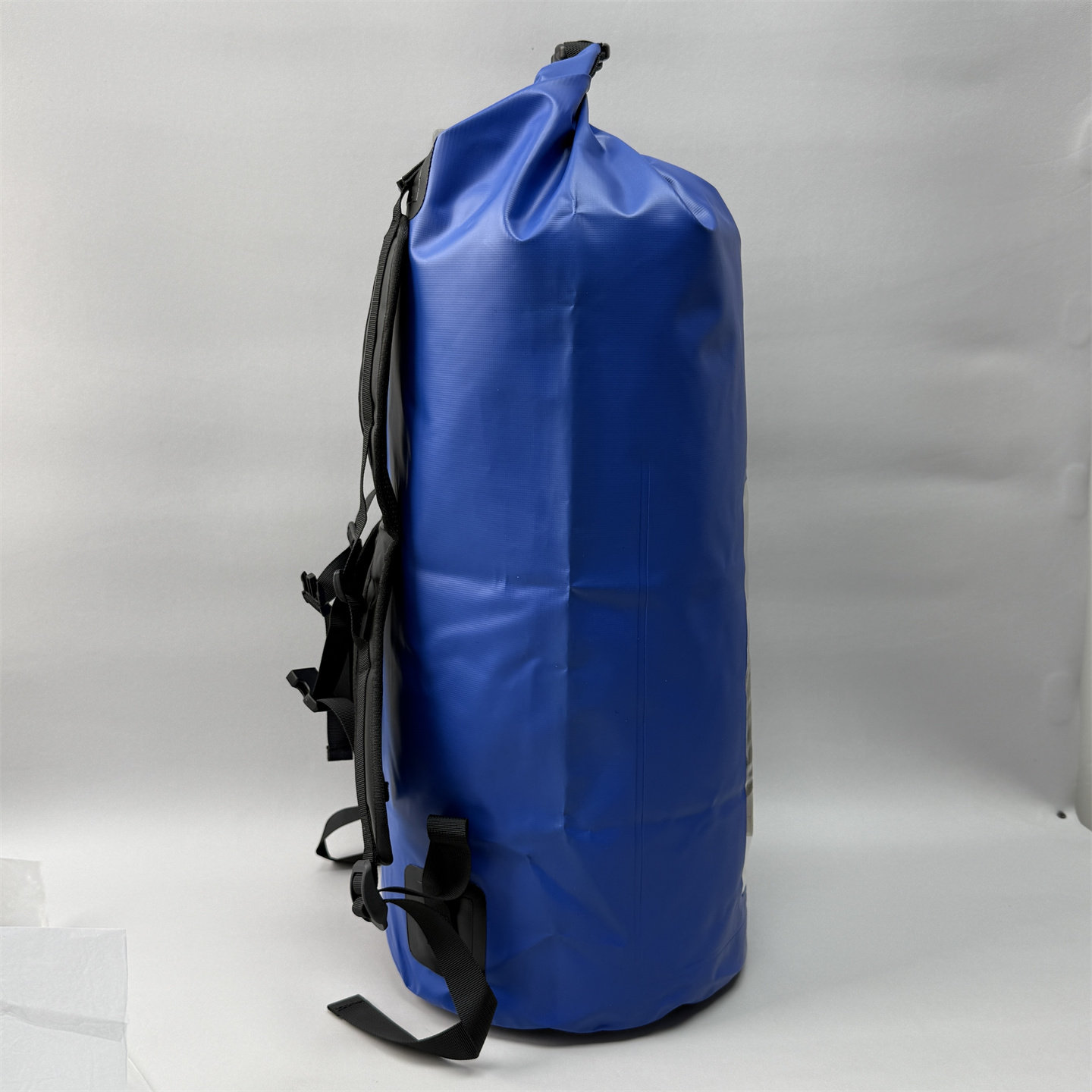 Side view of the blue 40L waterproof dry bag backpack showcasing its durable roll-top closure and thick material.