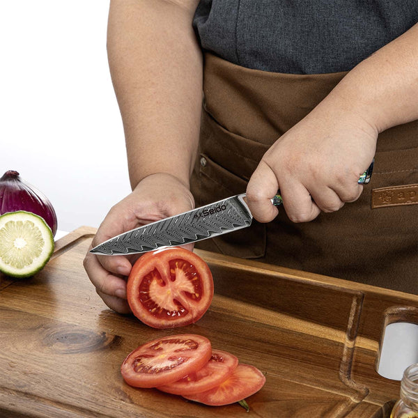 A chef using the Awabi utility knife to slice a tomatoe against a cutting board