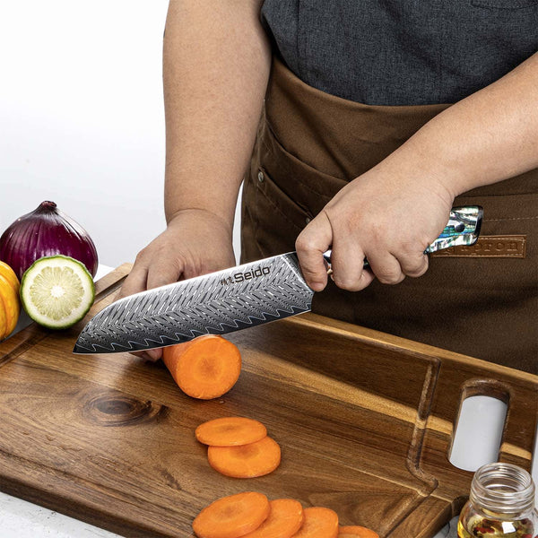 A chef using Seido's Awabi Santoku knife to cut a carrot against a cutting board