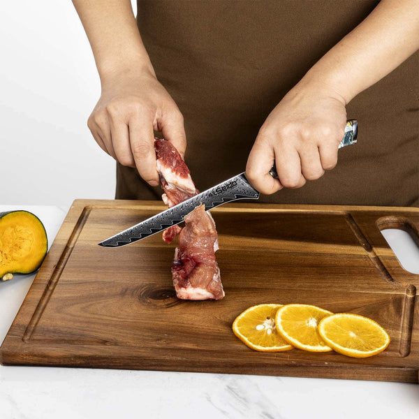 A chef using the Awabi boning knife to carve meat flesh off a bone