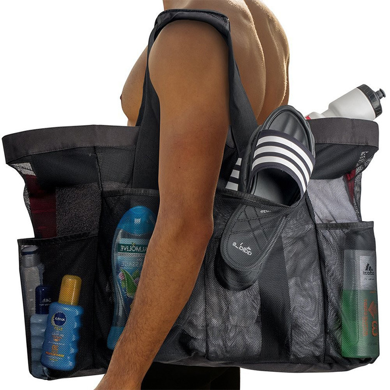 A person carrying the black Duck Camp large mesh gear tote on their shoulder, filled with sandals, sunscreen, and water bottles for the pool.