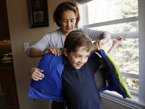 Woman putting on a bulletproof vest to a little boy
