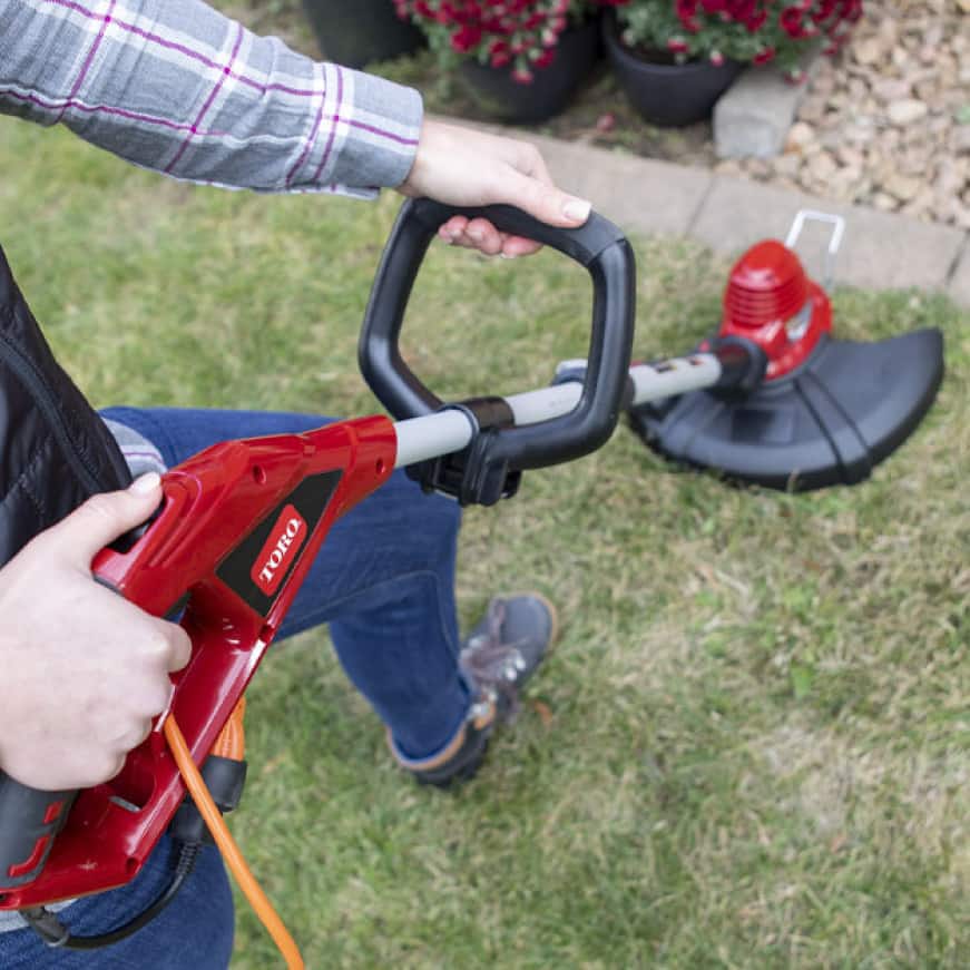 Close up of trimmer handle while cutting through thick grass