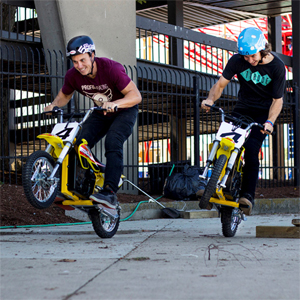 Razor; MX650; Electric Motor Cycle, Two Boys Riding each with Front Wheelie