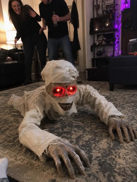 Guests reacting to the crawling mummy in a decorated living room