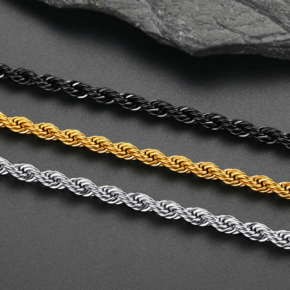 Three rope chains in black, gold, and silver on a dark surface.
