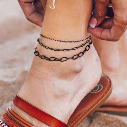 Woman  showing 2mm, 3mm, and 6mm widths black paperclip anklet at the beach