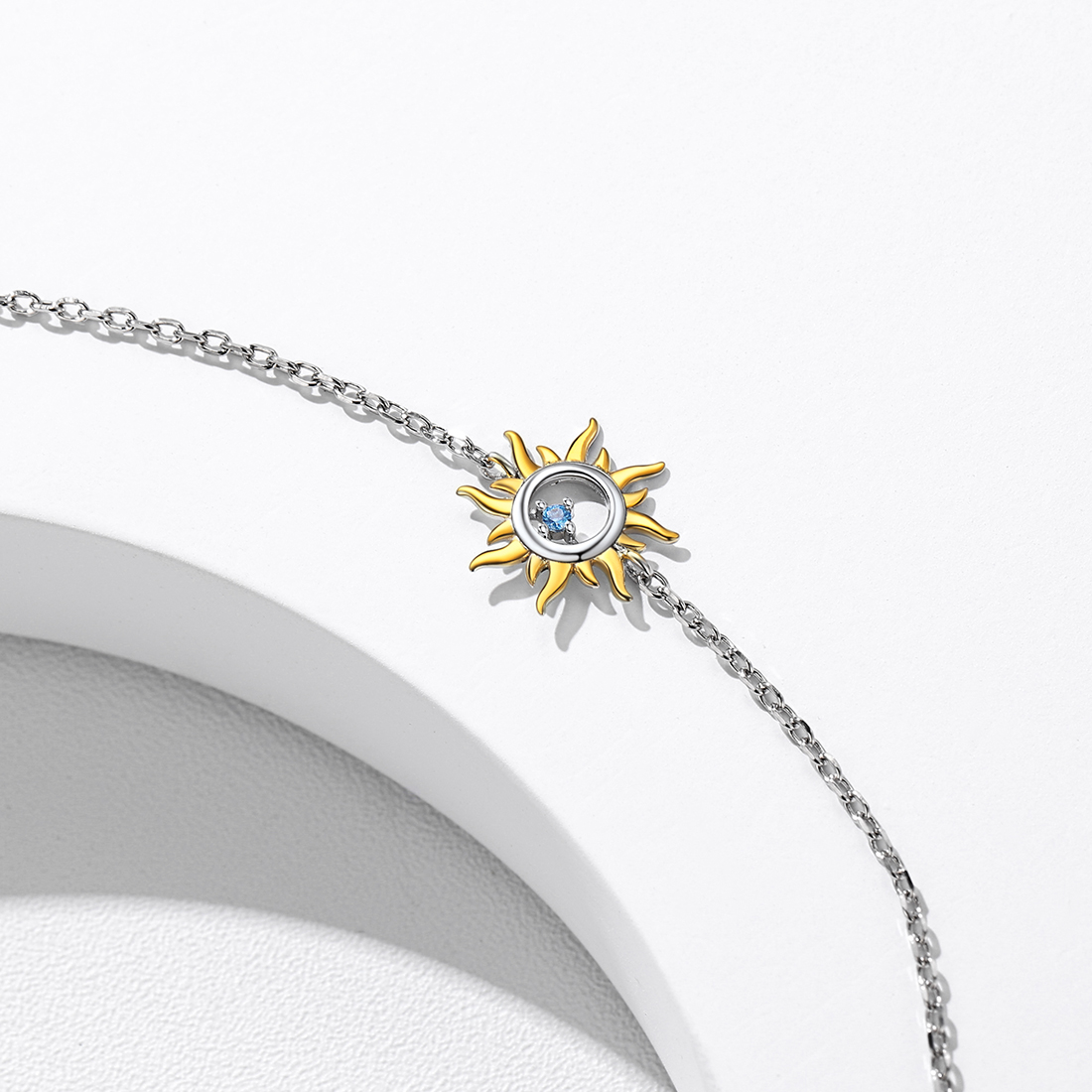 Close-up of a star-shaped sun charm with blue center stone on a S925 silver anklet, detailed design.