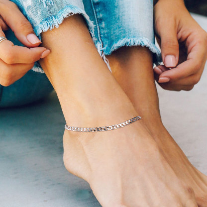 Simple silver chain anklet worn on ankle with frayed blue jeans