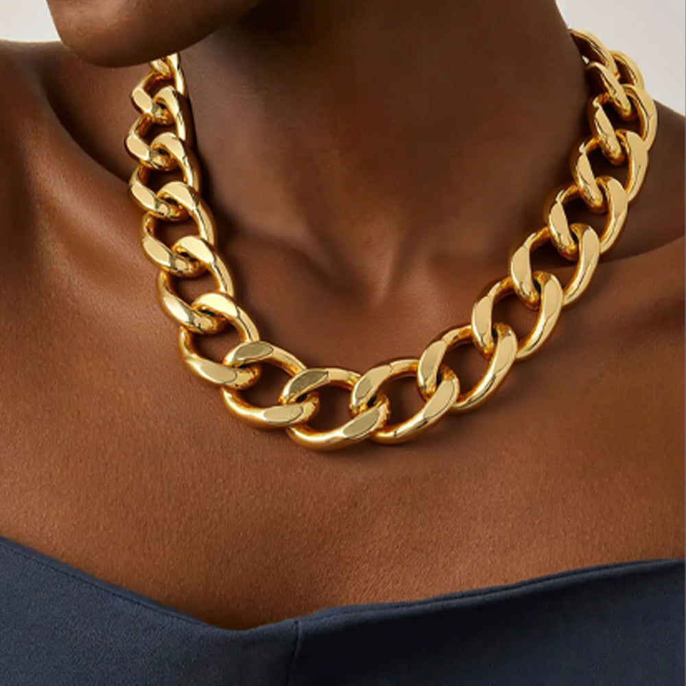 Gold chain necklace on a person with a neutral background