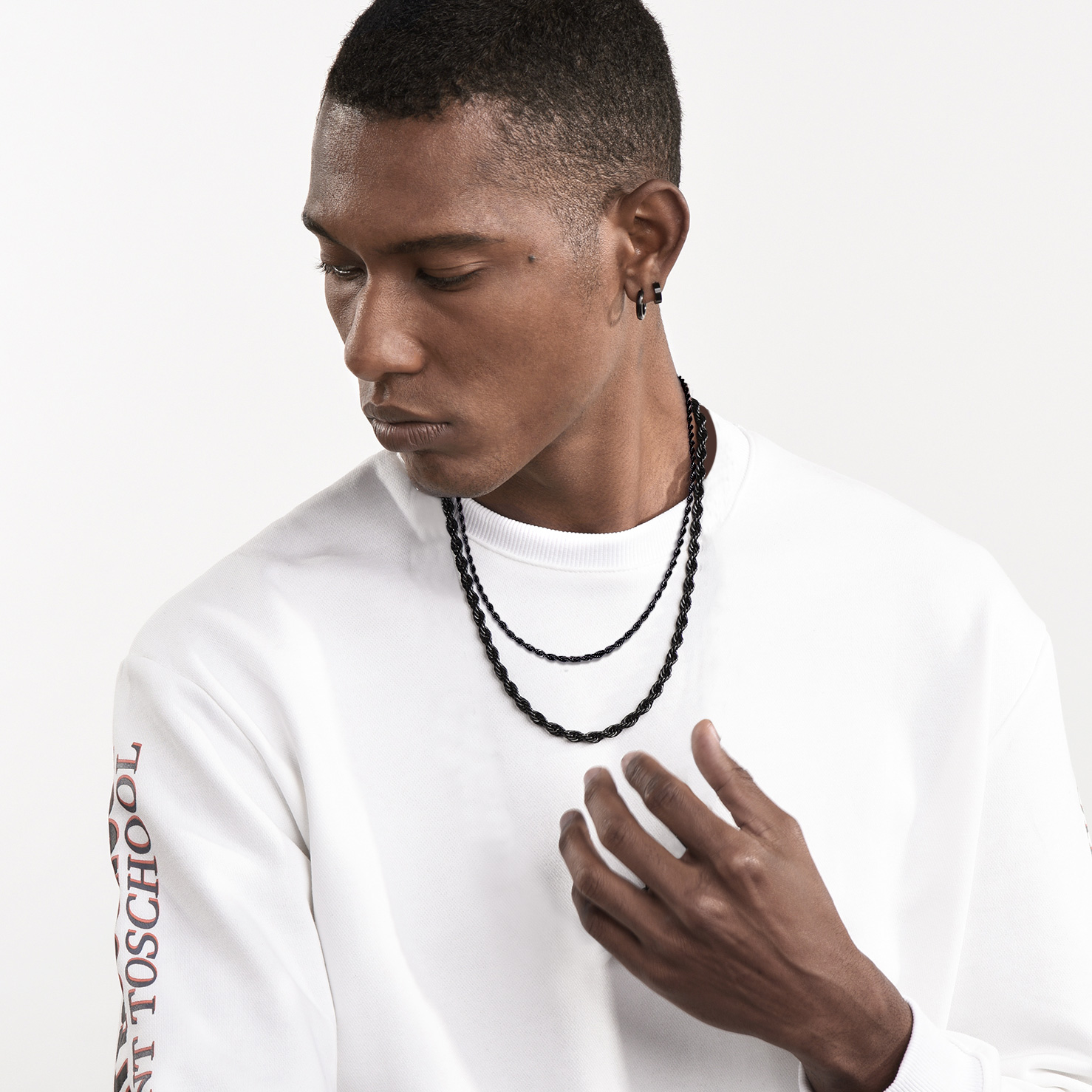 Man wearing layered black rope chain necklaces