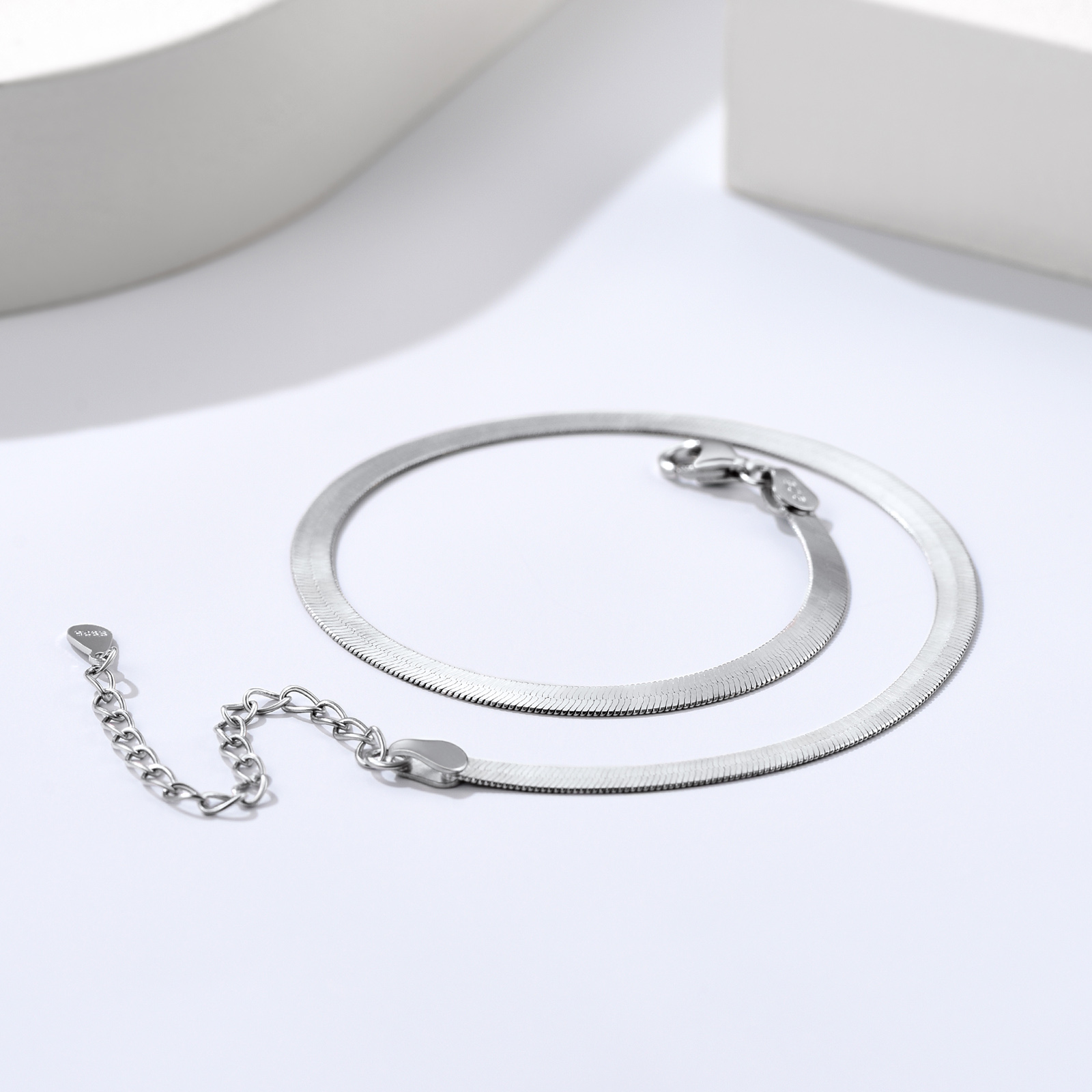 Detailed still life of a polished sterling silver snake chain necklace with clasp
