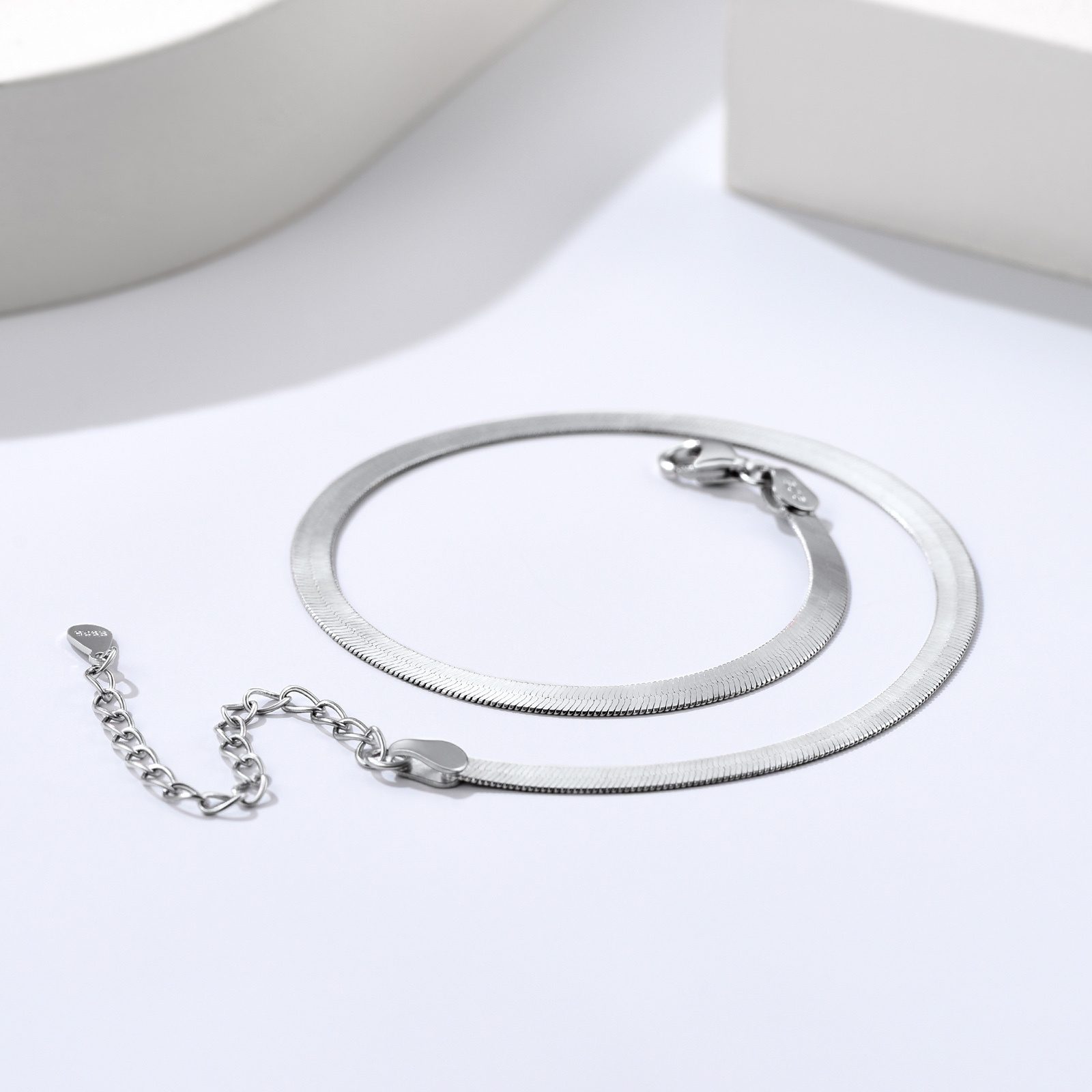 Detailed still life of a polished sterling silver snake chain necklace with clasp
