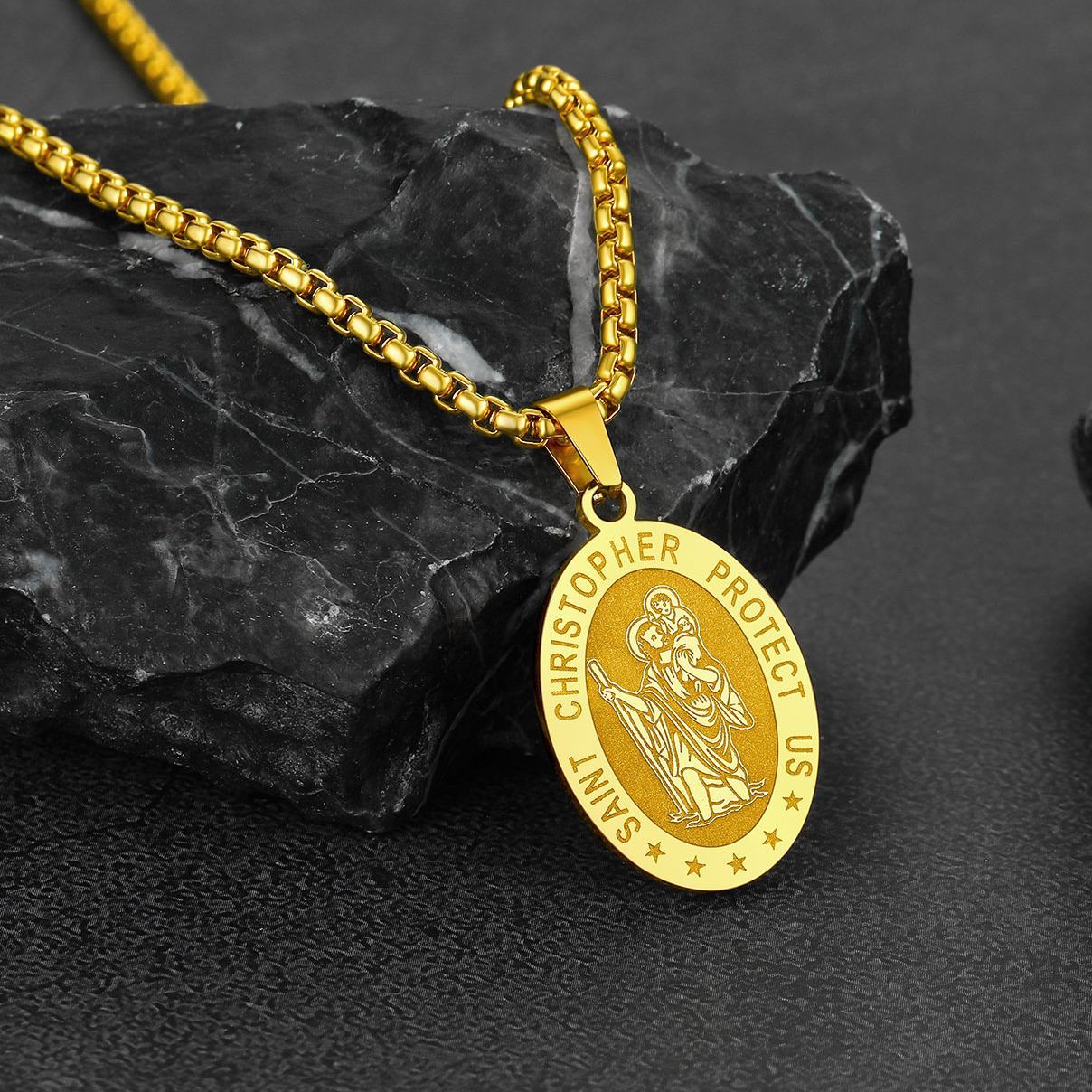Gold Saint Christopher necklace on black stone background