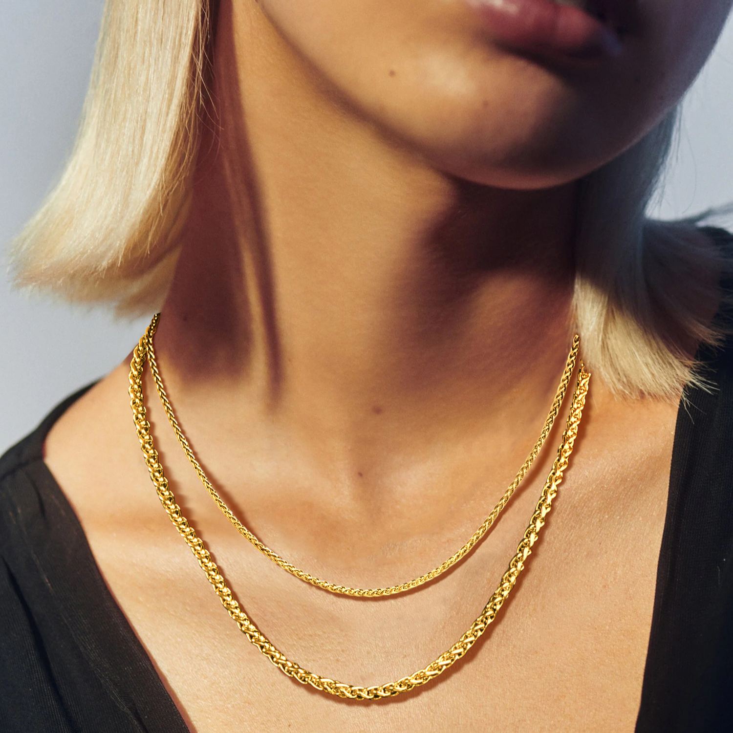 Woman wearing gold wheat chain layered necklace