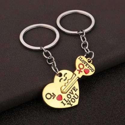 Two gold heart-shaped keychains with silver key rings, one shaped like a smiling face and the other like a key, both engraved with 'I LOVE YOU' and a small red heart, displayed on a dark textured background.