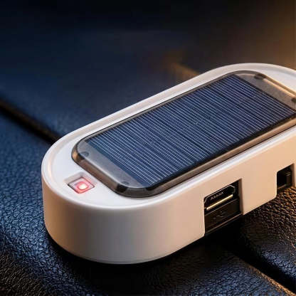 A close-up of a white portable solar power bank with a built-in solar panel on top, featuring a red power indicator light and USB-C port, resting on a dark textured surface.