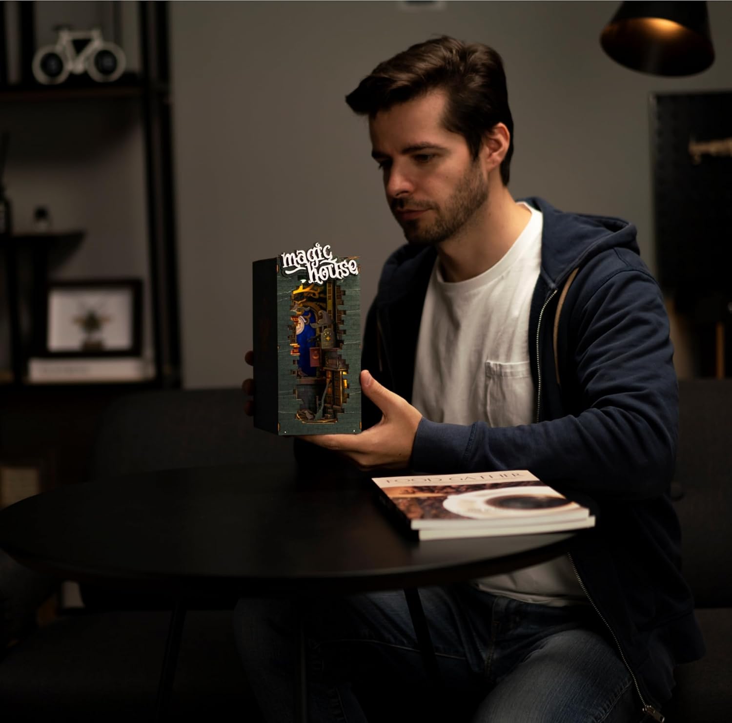Man holding the assembled Magic House 3D wooden puzzle, showing the lighted wizard shop interior.-uFunSpace