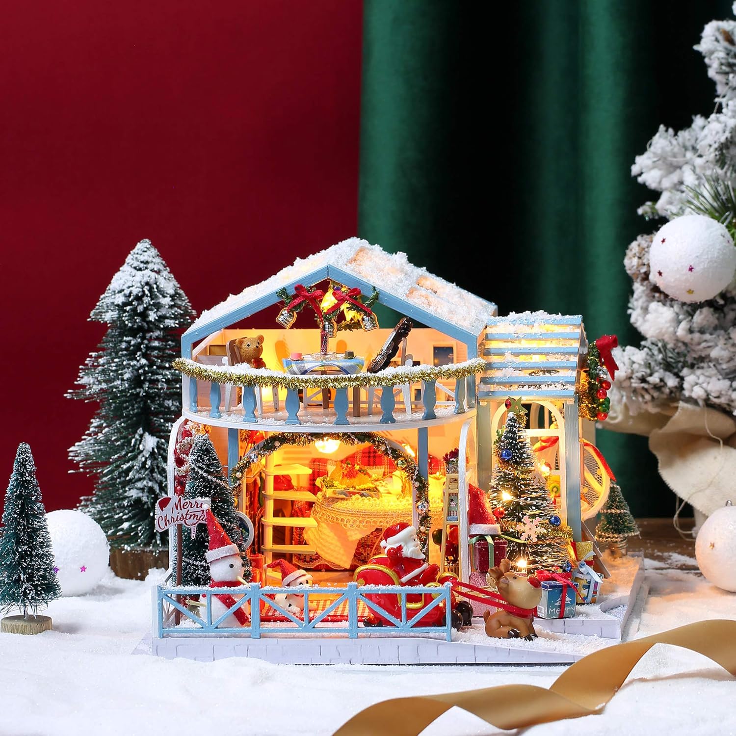 Cozy interior detail showing a red plaid miniature sofa, fireplace with hanging stockings, and a Christmas wreath-uFunSpace