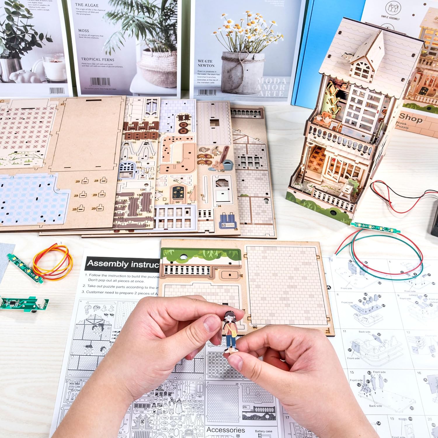 Hands assembling the 3D wooden puzzle Coffee Shop, showing circuit boards for LED lights and wooden parts.-uFunSpace