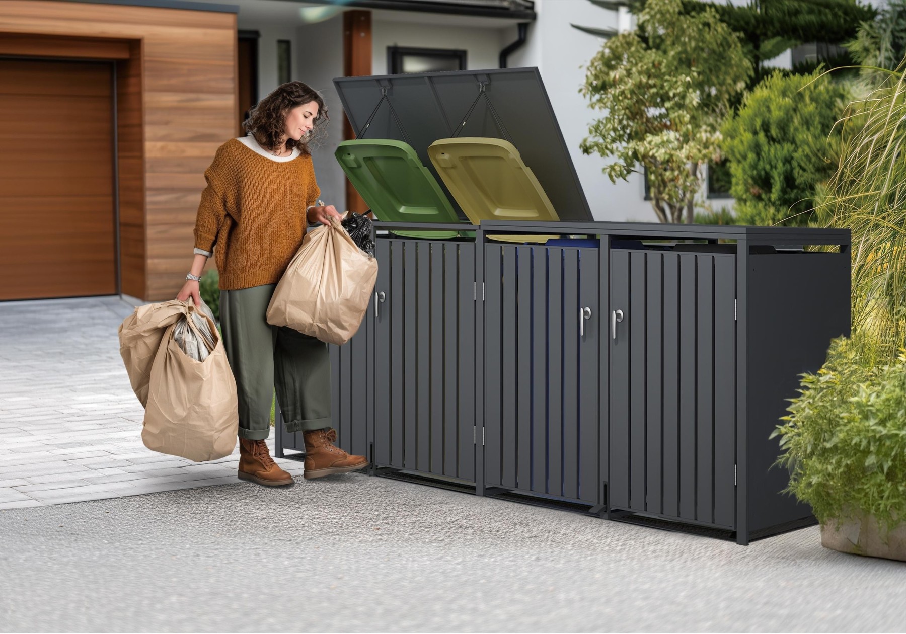 Person using a pedal-operated quad wheelie bin store with colour-coded bins