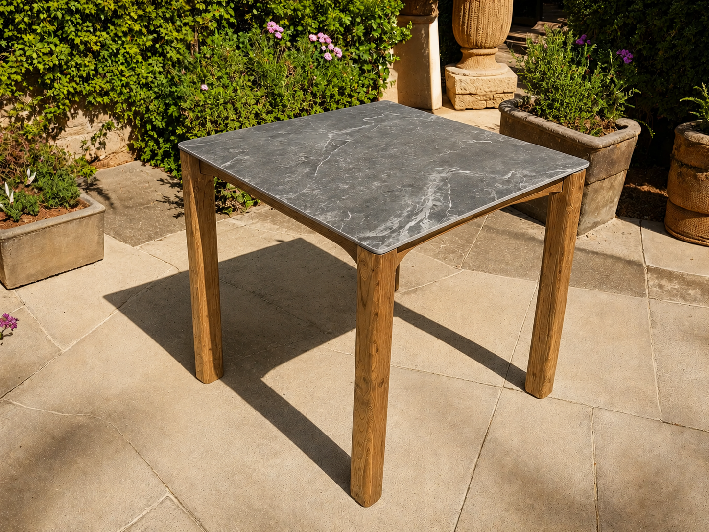 Faro reclaimed teak and grey ceramic outdoor dining table in a sunny garden patio setting