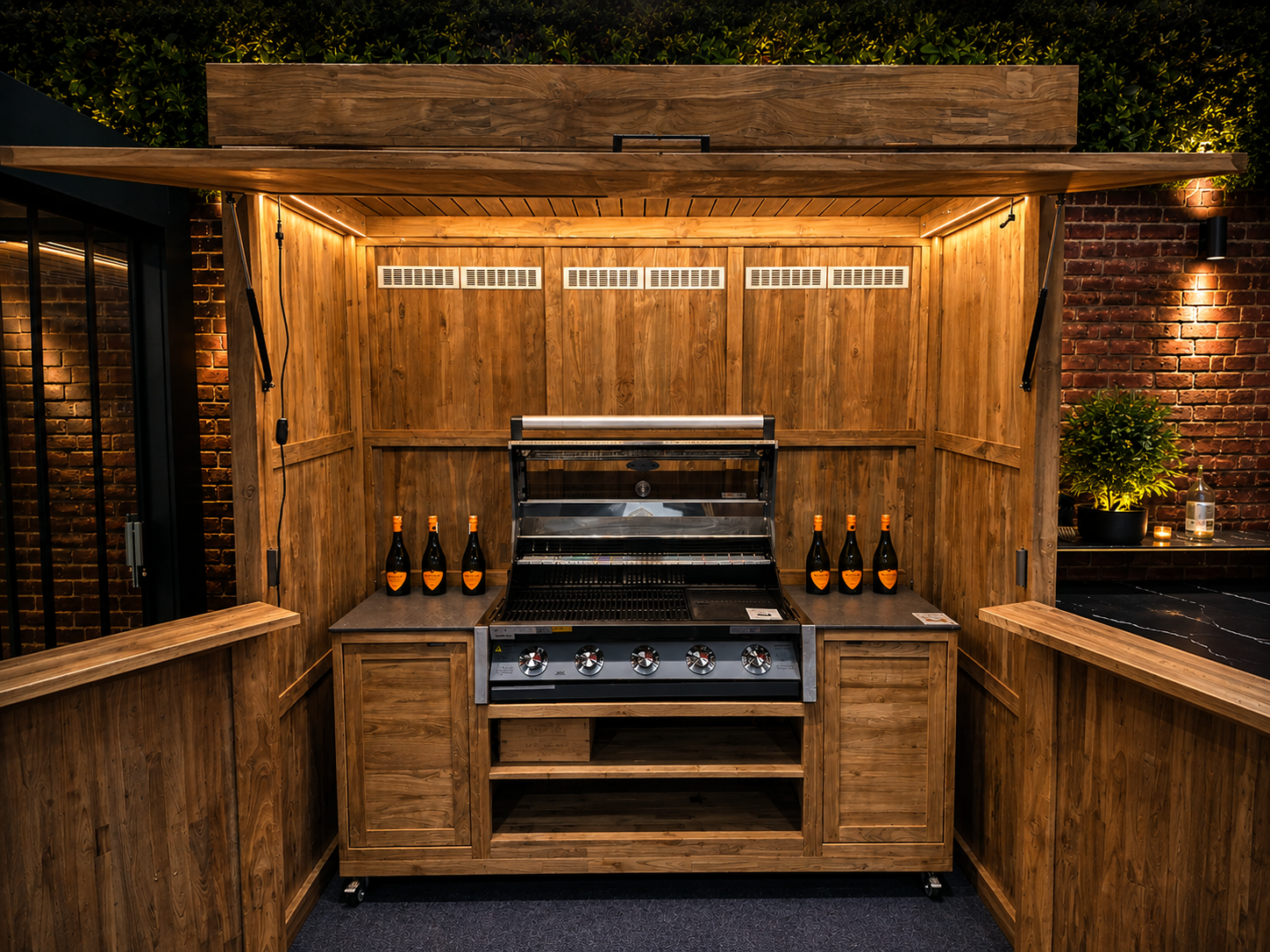 Bari Teak Kitchen Storage Cabinet with built-in BBQ and outdoor kitchen storage, illuminated at night